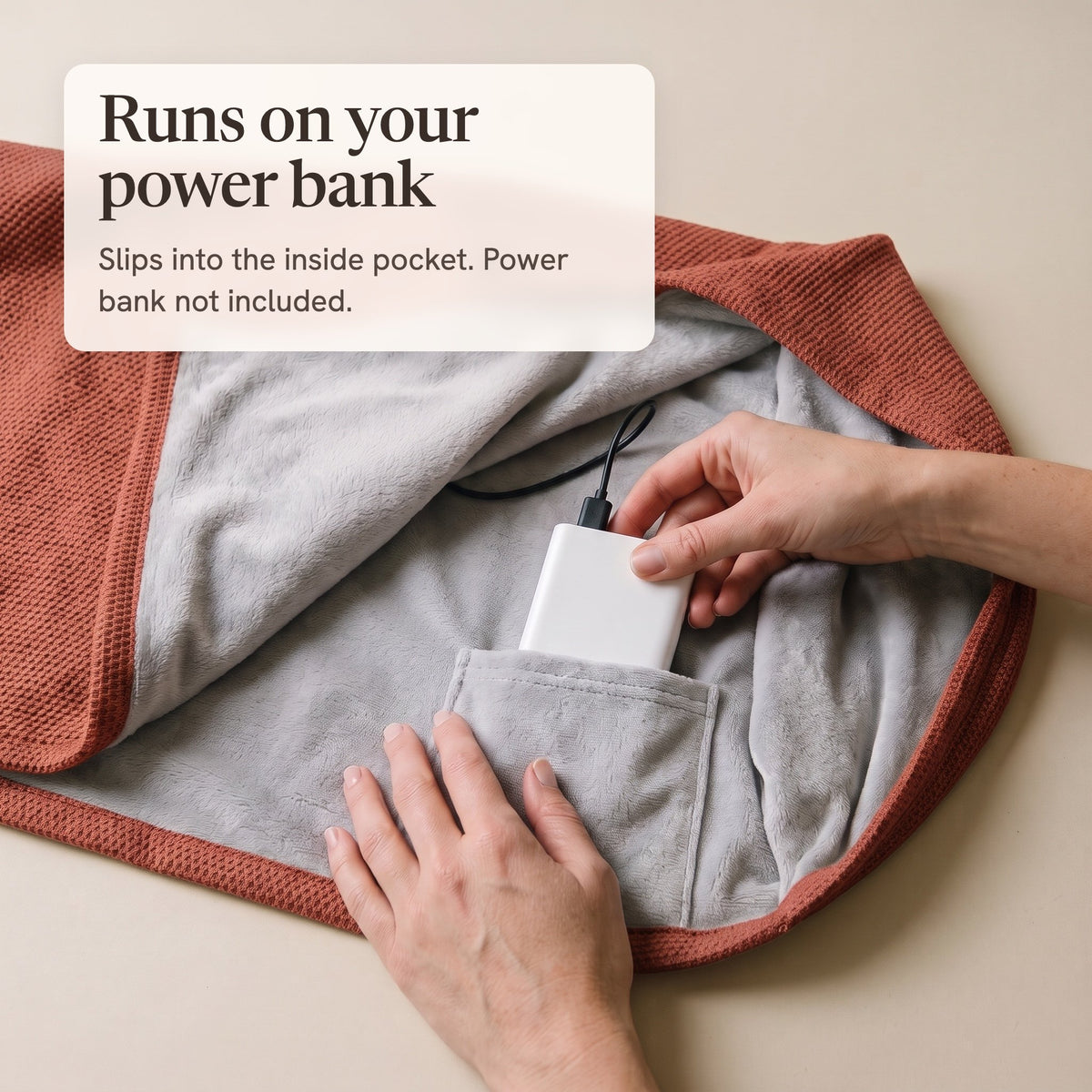 Hands sliding a white power bank into the inside pocket of the brick red wrap