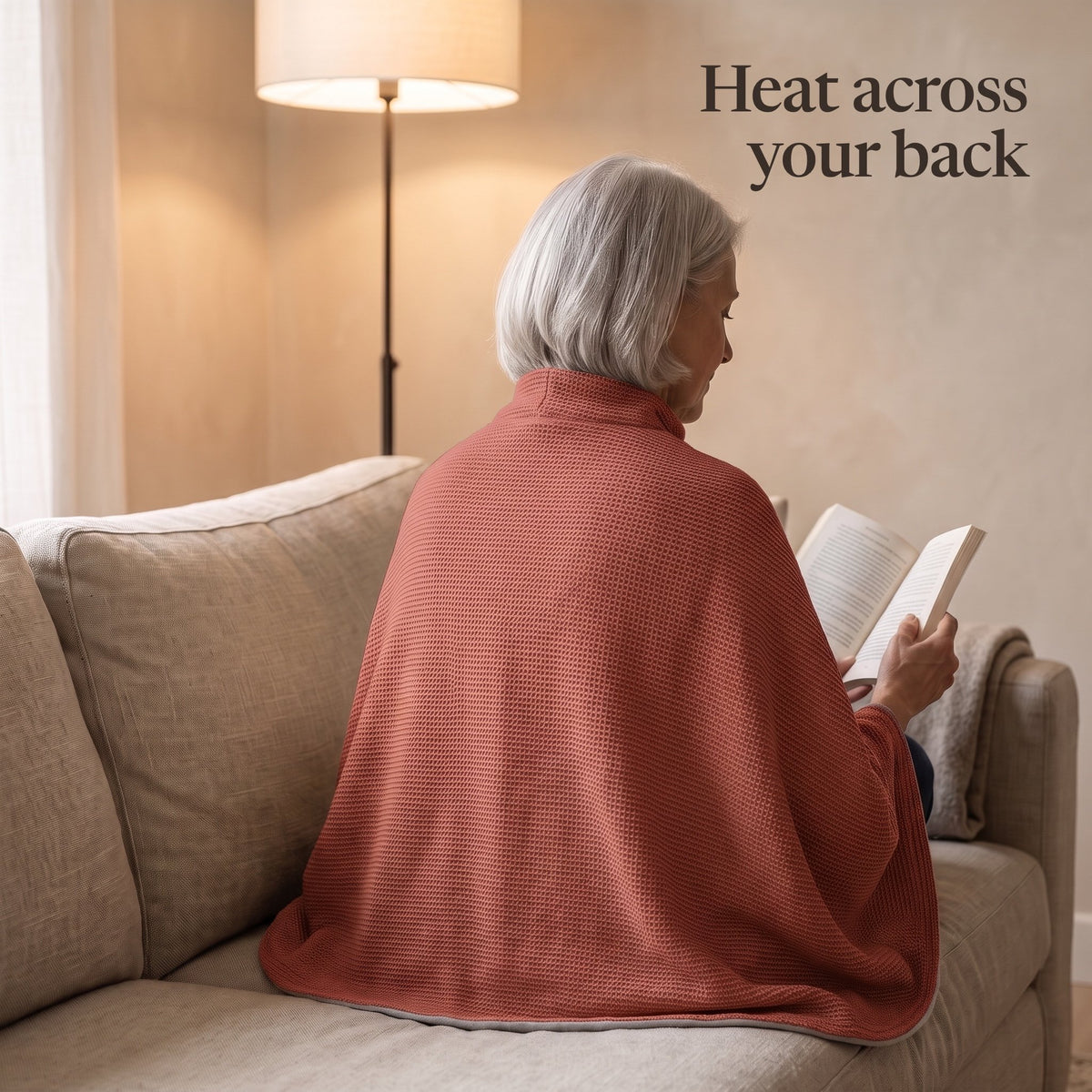 Woman reading on a sofa, the brick red wrap over her shoulders and back