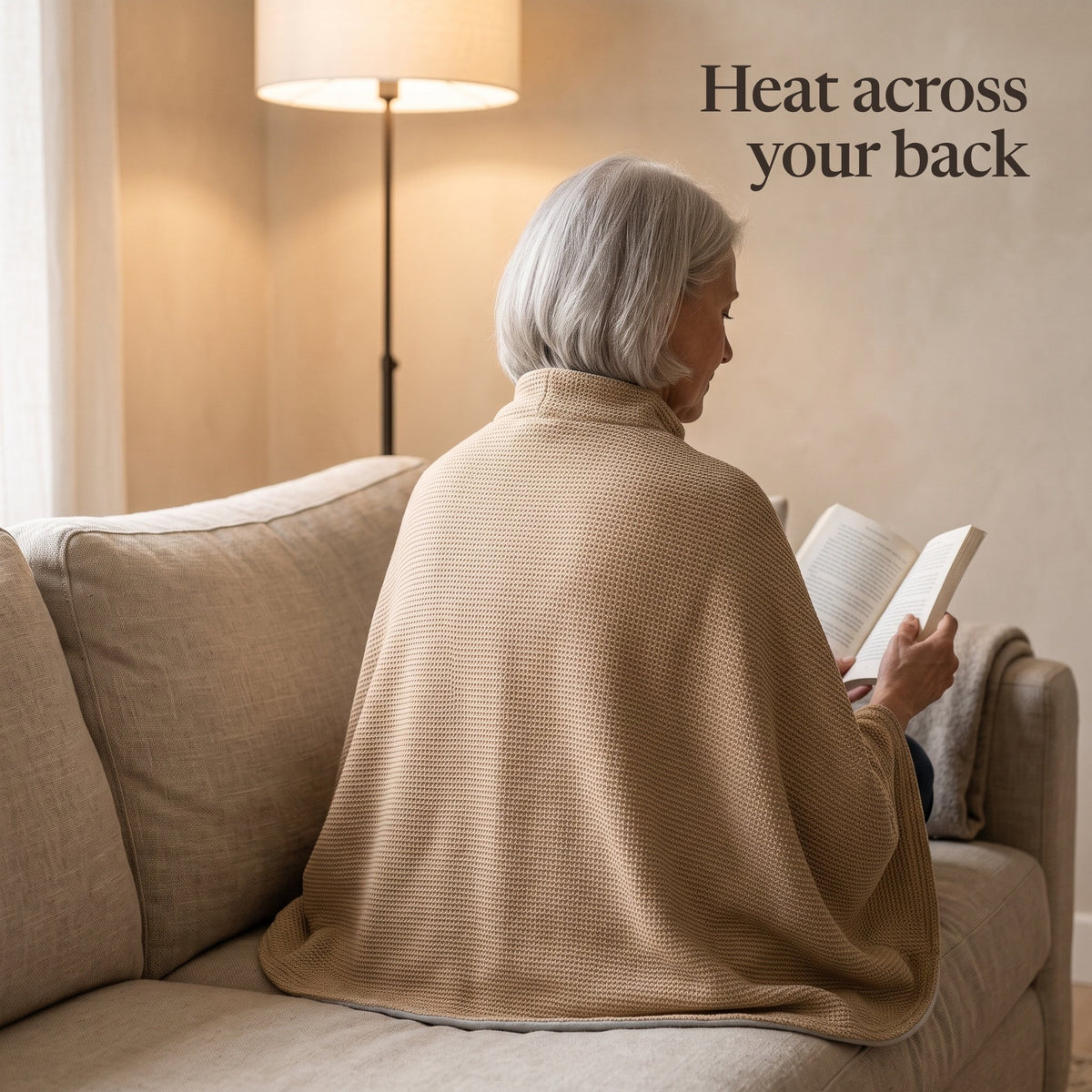 Woman reading on a sofa, the camel wrap over her shoulders and back