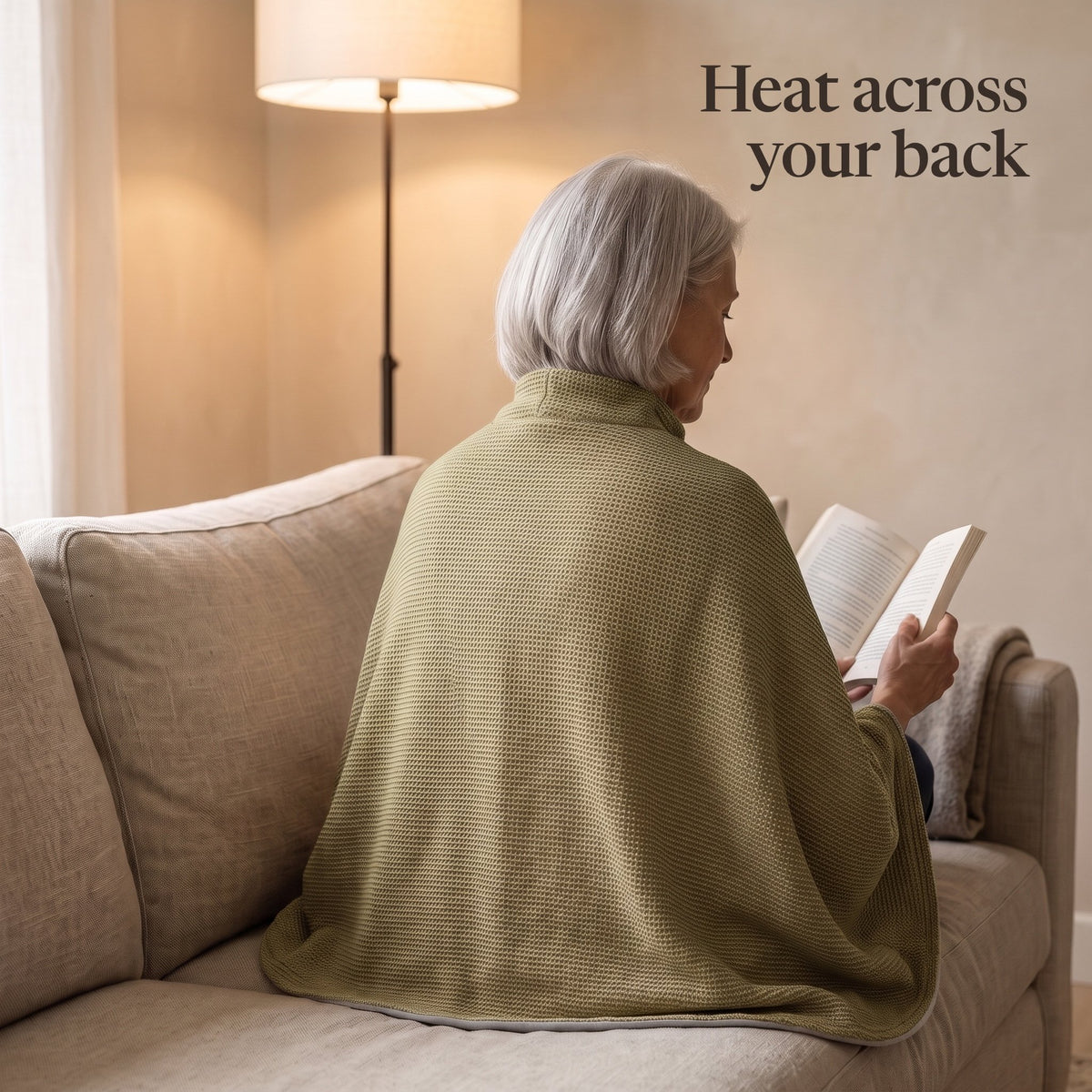 Woman reading on a sofa, the olive wrap over her shoulders and back