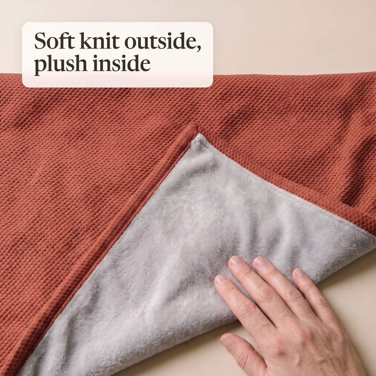 Folded corner of the brick red wrap showing the waffle knit and grey plush lining