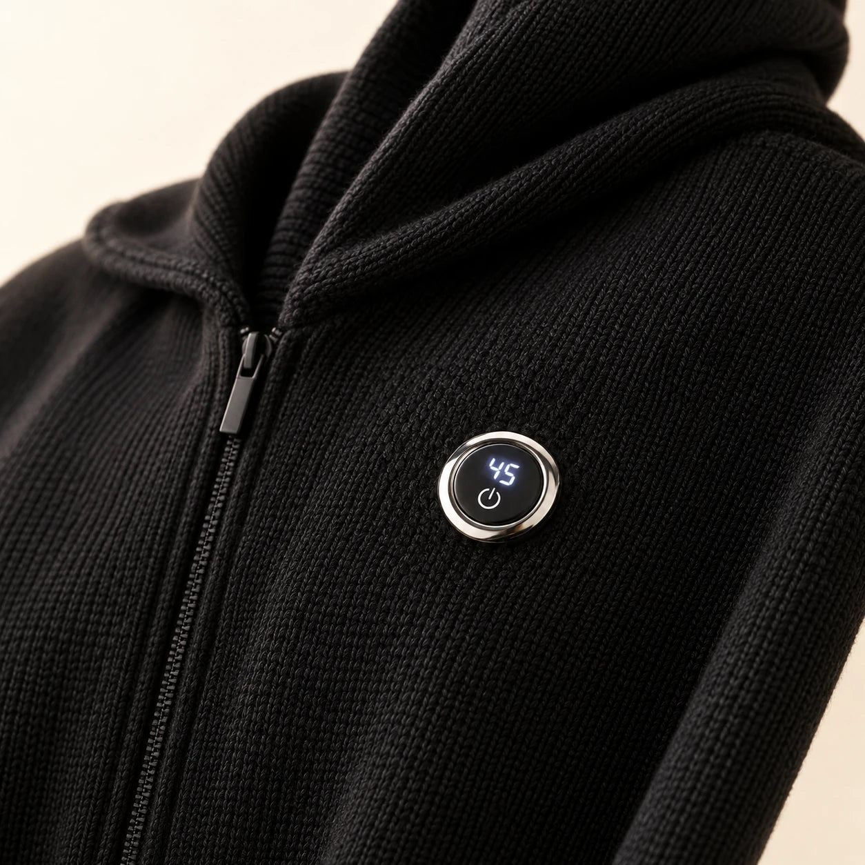Round silver-rim control on the black knit poncho beside its front zipper.